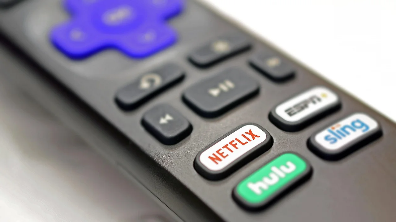 Pessoa usando controle remoto diante de uma televisão conectada