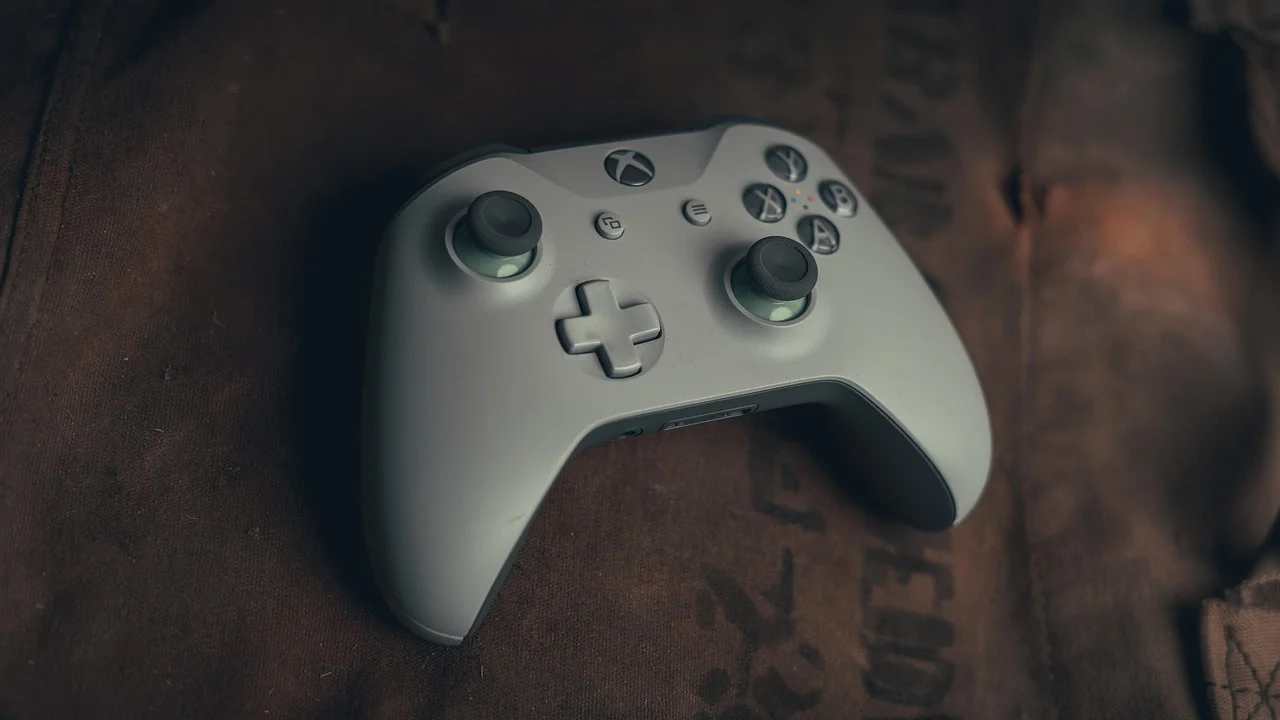 Jogador usando controle de Xbox diante de monitor gamer