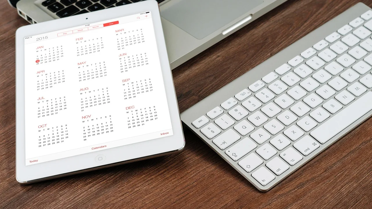 Agenda de trabalho organizada ao lado de computador portátil.