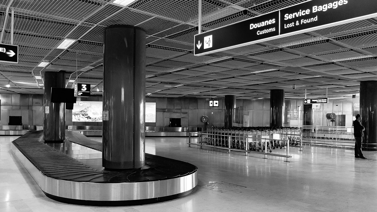 Passageiro observa a esteira de bagagens vazia no aeroporto.