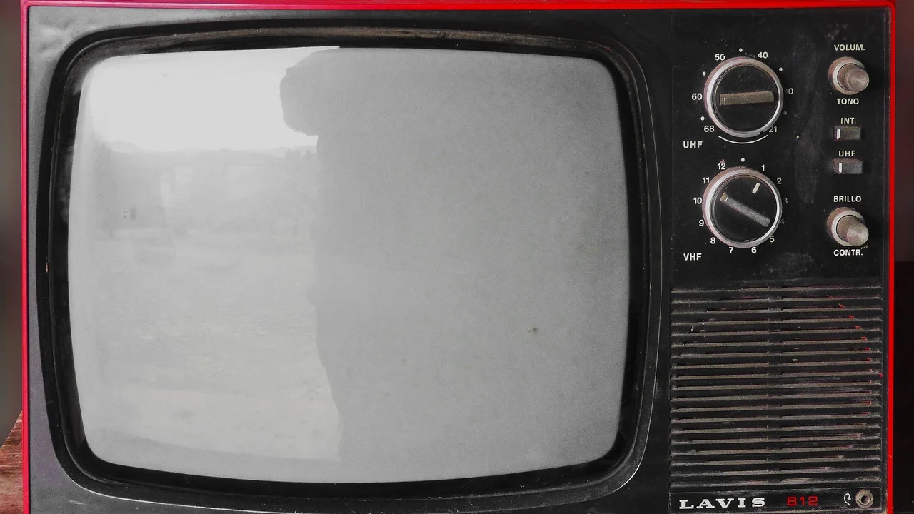 Controle remoto diante de uma Smart TV com conteúdo em UHD